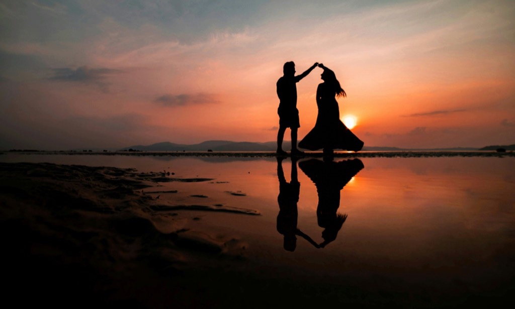 Two figures dancing at the shoreline.